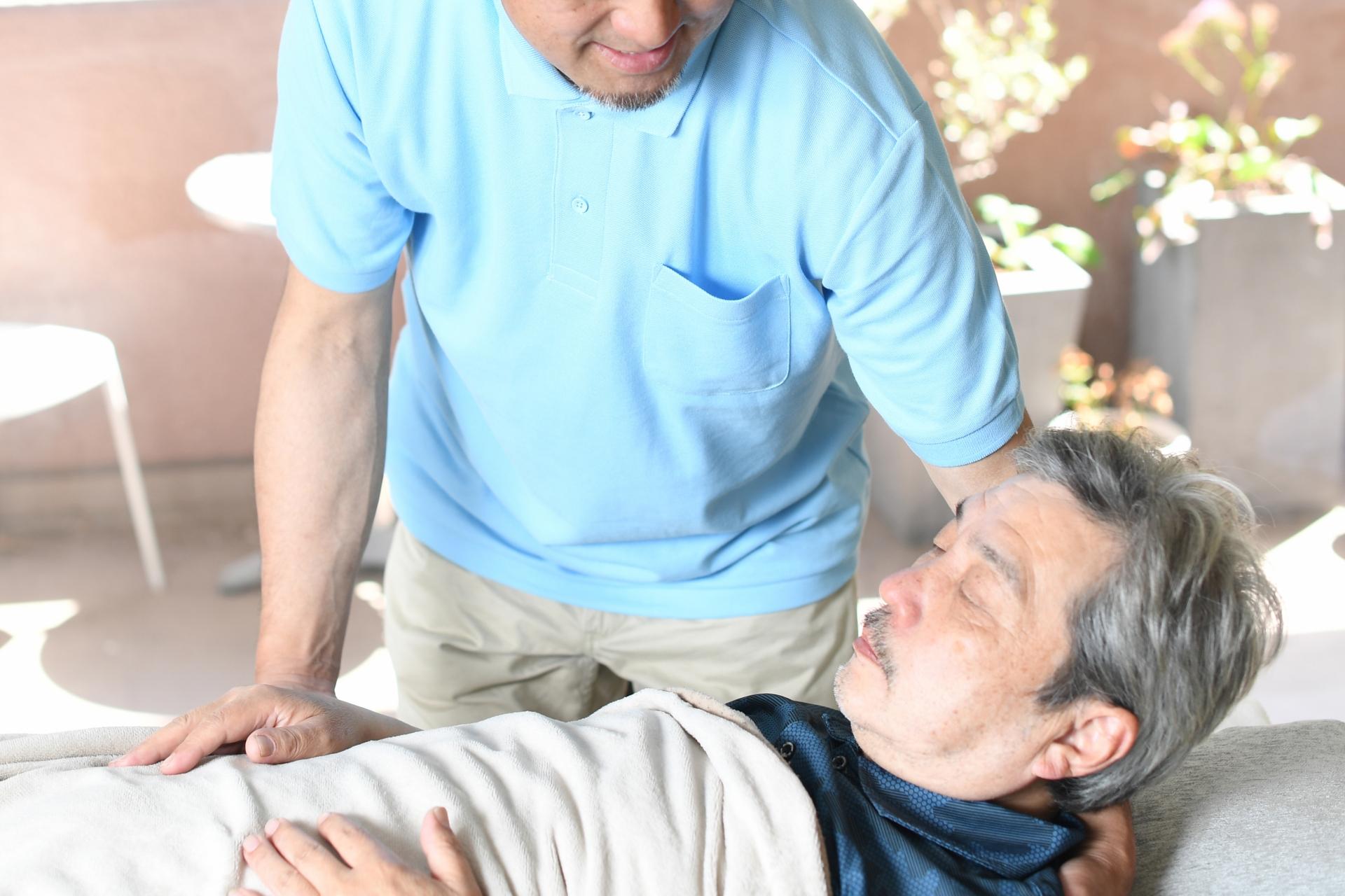 高齢者をベッドで介助する男性介護士