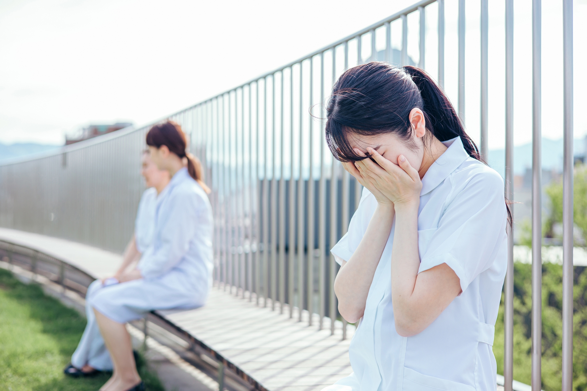 病院の屋上で泣く女性看護師