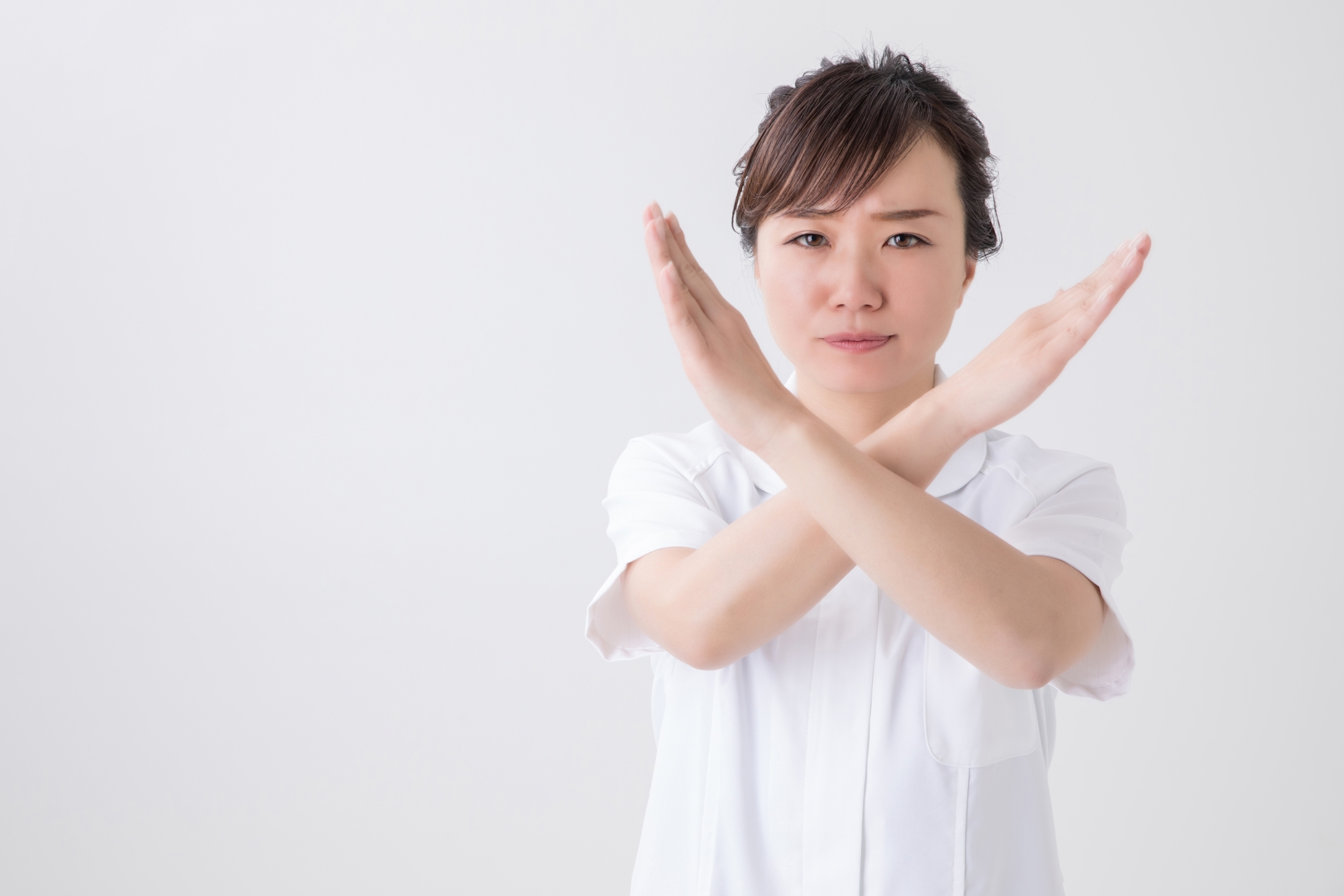 バツを作る白衣の女性