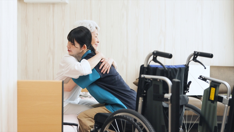 高齢者の移乗介助をするアジア人介護士