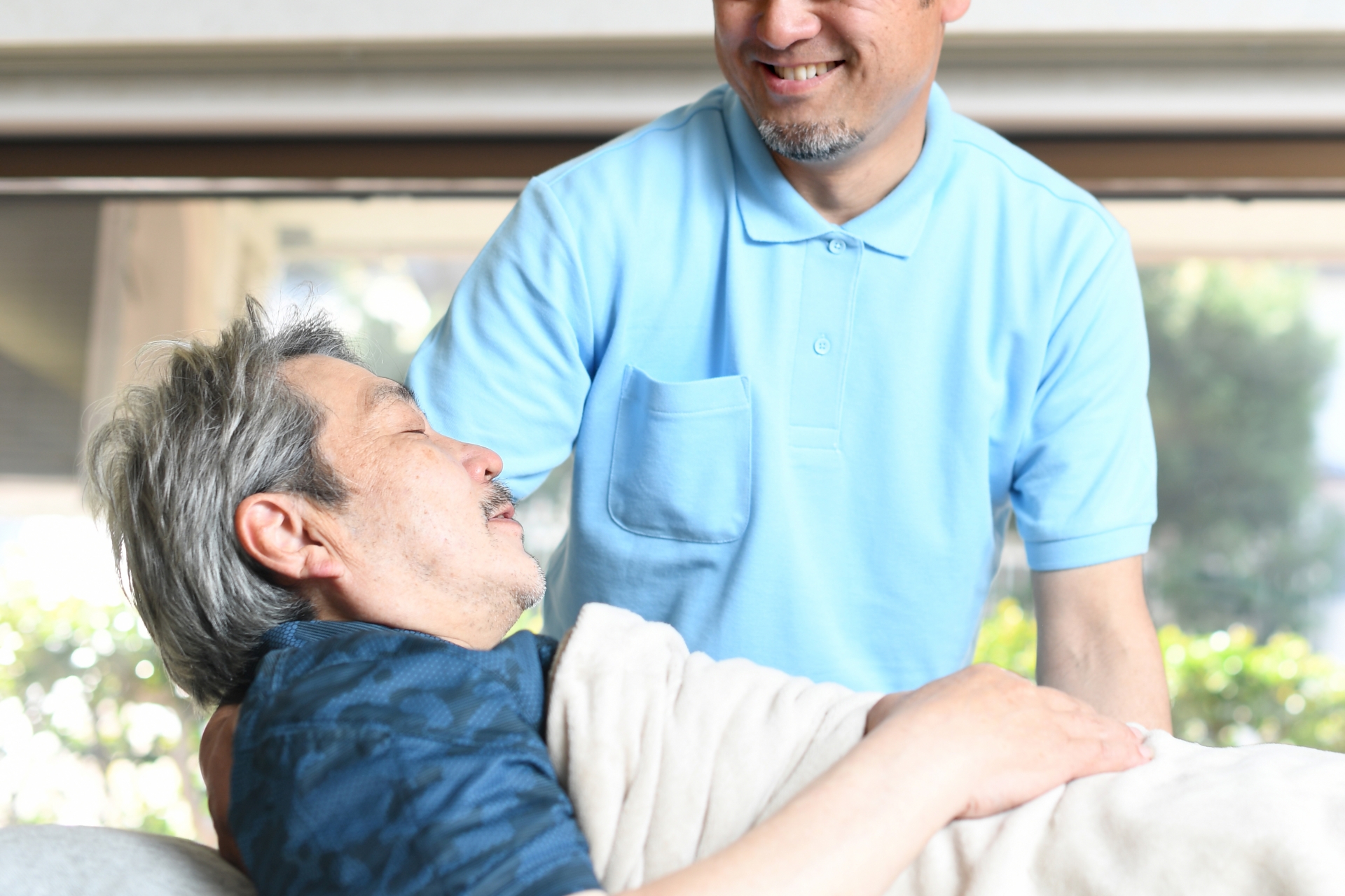 高齢者をベッドで介助する男性介護士