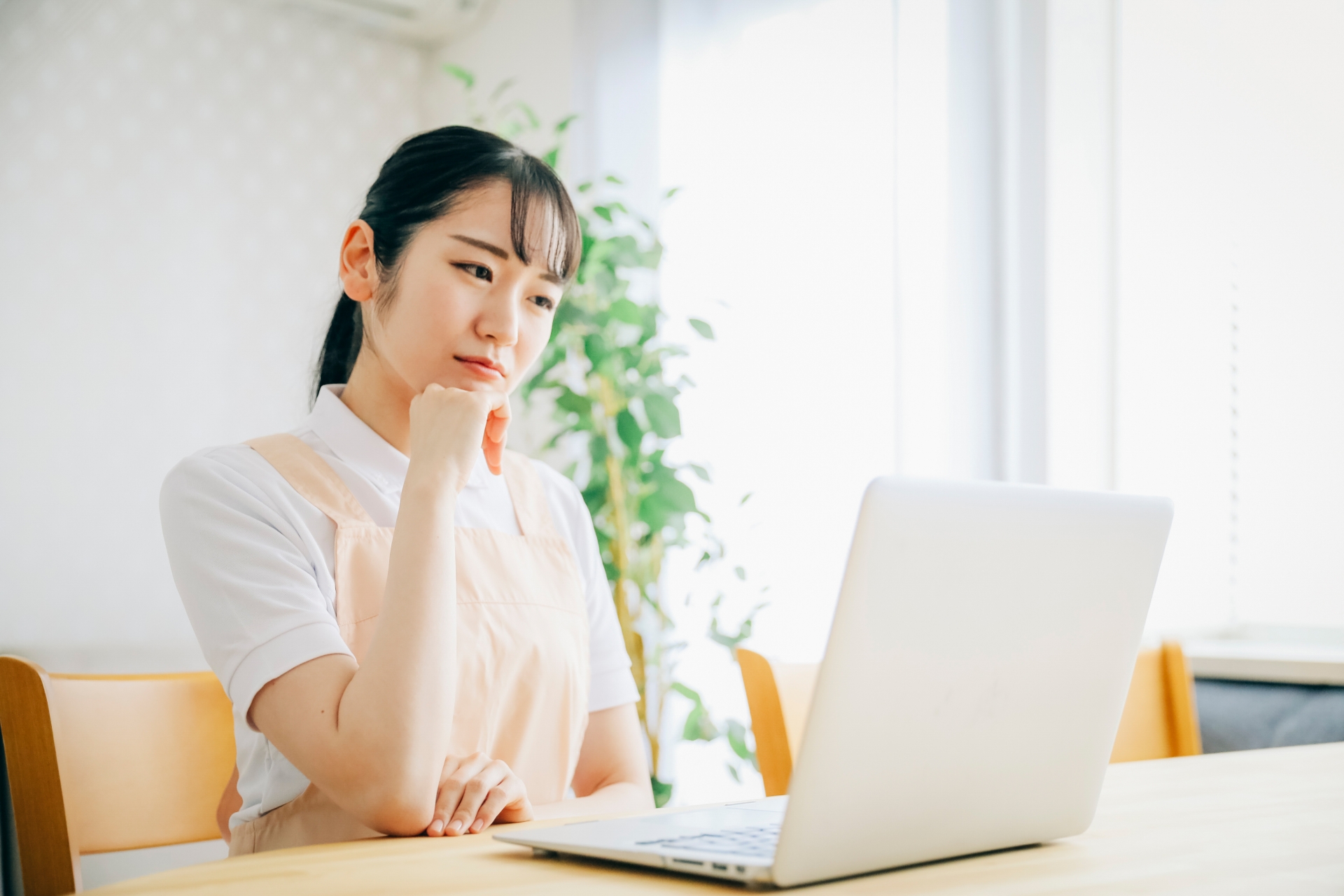 パソコンを使うエプロン姿の女性（考える・困る）