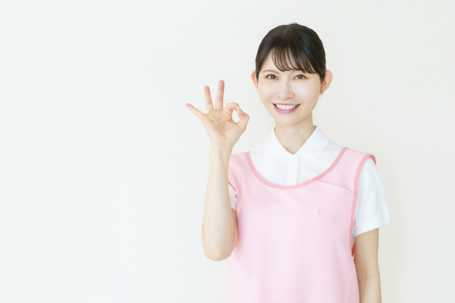丸のポーズをする若い日本人女性介護士