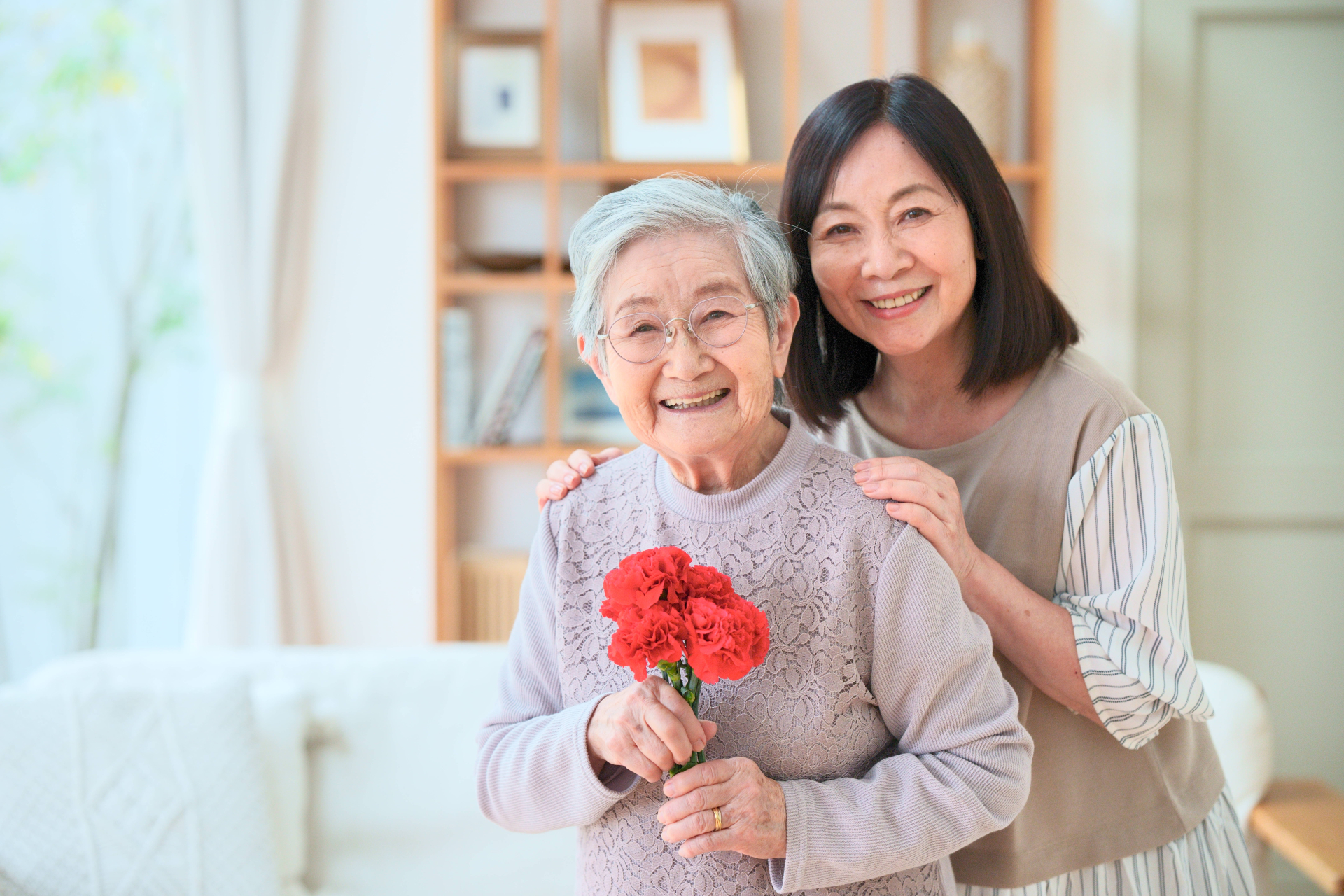 笑顔で花を持つ高齢女性と女性