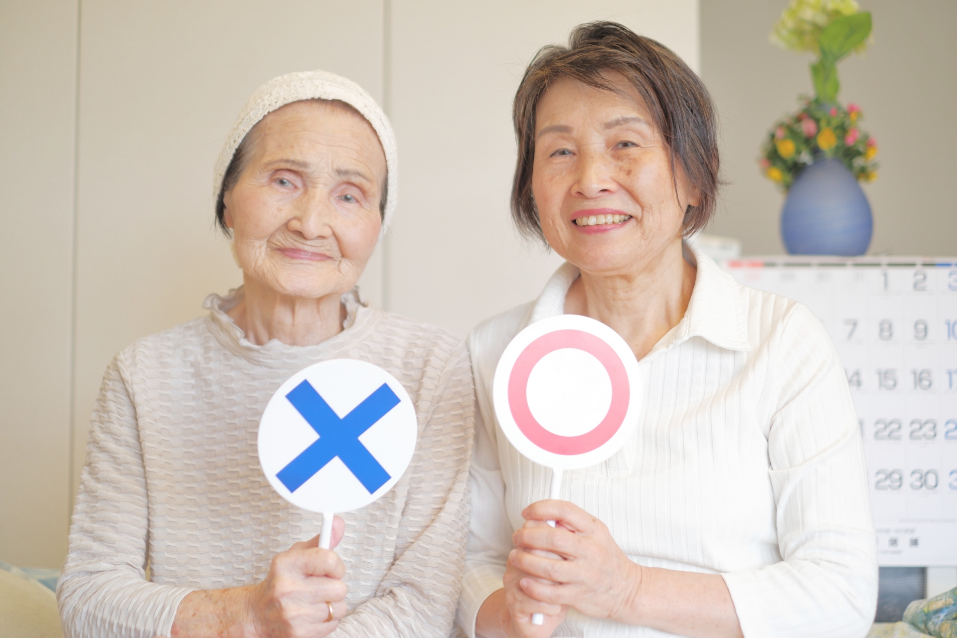 老老介護　マルバツの札を持つ年配母娘