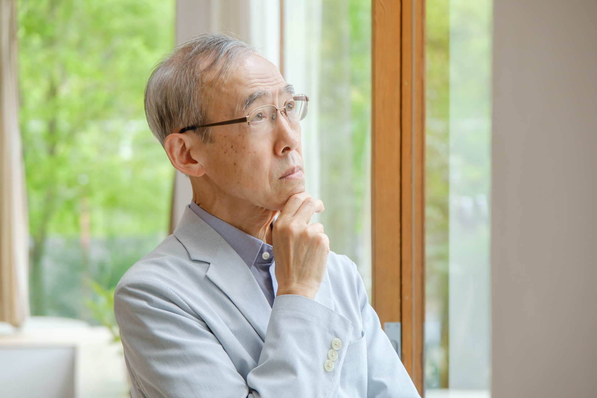 考え事をする高齢者の男性